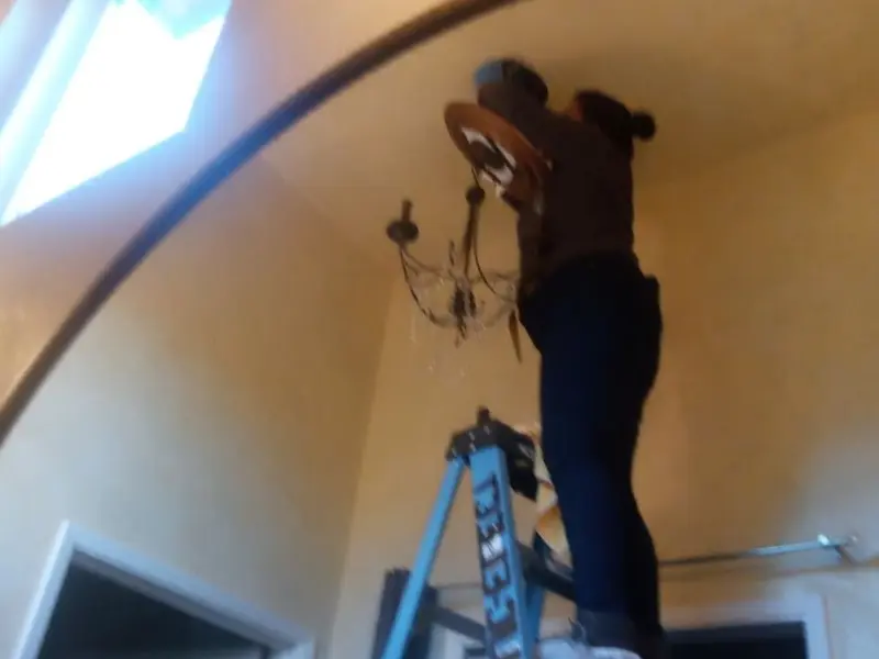 Electrician installing a chandelier in a Alsace residence